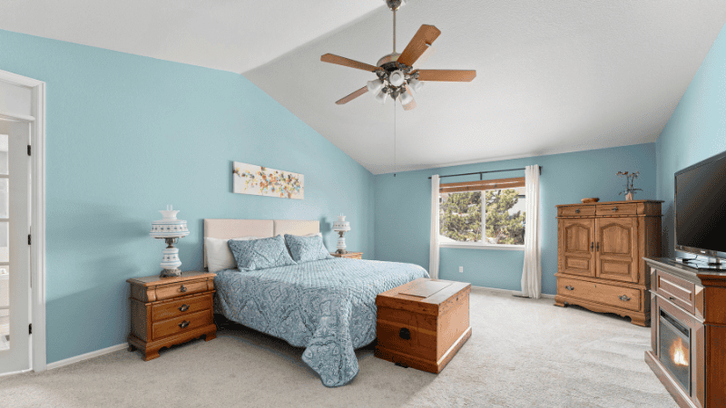 The classical bedroom in a modern blue style is paired with a wooden ceiling fan.